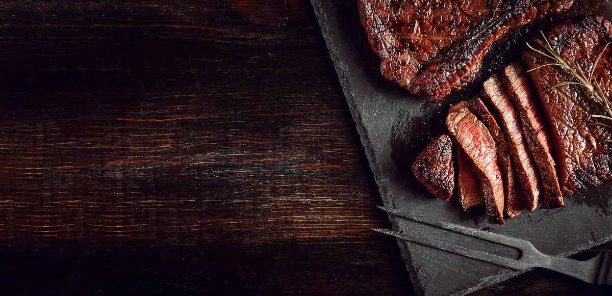 Sliced beef on a dark stone board with a wooden background from Dun Rite


